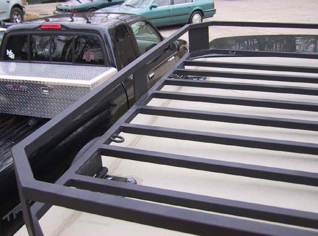 Black tubular steel roof rack with slats, black pickup with toolbox behind