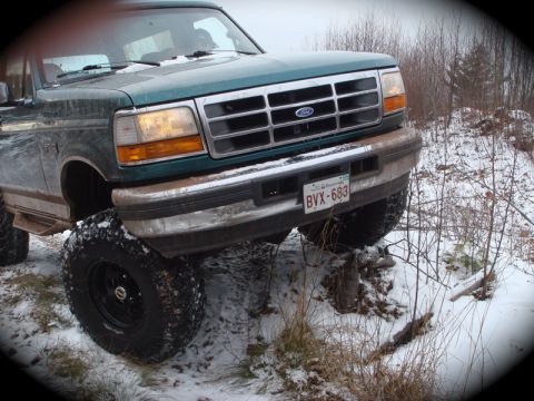1996 Ford Bronco - This Ford truck is navigating rough, snowy terrain with its front wheels elevated.