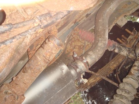 1996 Ford Bronco - Close-up view of the exhaust system components, showing significant rust on the vehicle's undercarriage.