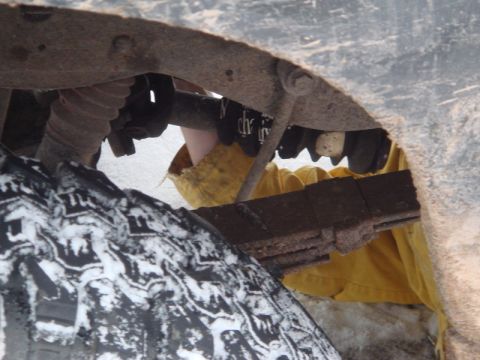 1996 Ford Bronco - A close-up view of the undercarriage reveals leaf springs and a tire covered in snow.