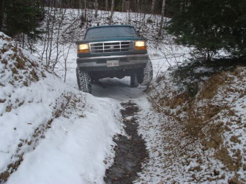 1996 Ford Bronco - Ford F-Series truck navigates a challenging snowy path with a visible license plate.