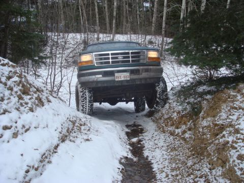 1996 Ford Bronco - This truck is navigating a challenging off-road trail in a snowy environment.