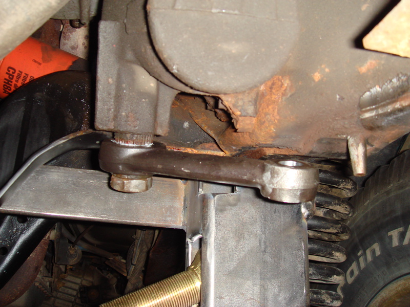 Close-up of rusty steering linkage and heavy-duty spring on a vehicle's undercarriage