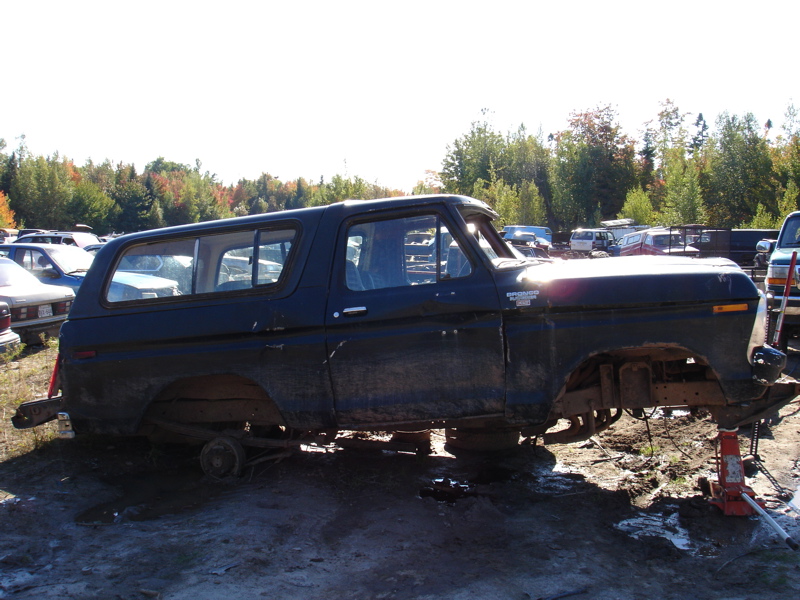 Black Ford Bronco body on jacks, missing wheels and front end