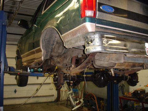 1996 Ford Bronco - Undercarriage view of a green Ford Bronco being serviced on a lift.
