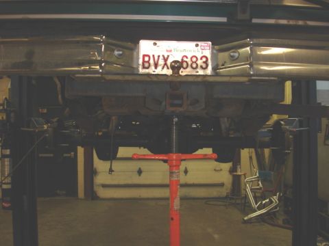 1996 Ford Bronco - The underside of a vehicle is visible as it is supported by a lift and a red jack.