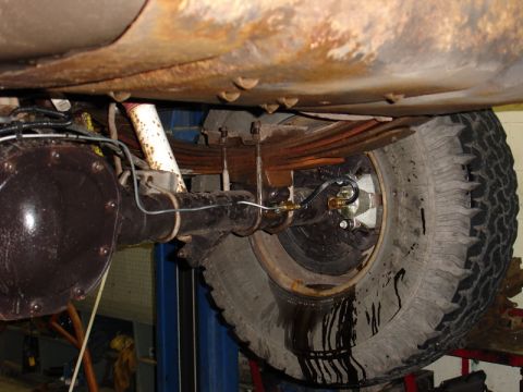 1996 Ford Bronco - The rear suspension and axle assembly of a vehicle, with fluid leaking from the brake lines onto the tire.