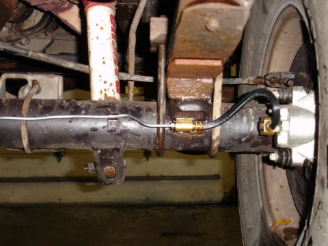 1996 Ford Bronco - Close-up view of the rear axle brake assembly, showing the caliper, brake line, leaf spring, and shock absorber.