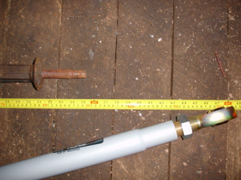 1996 Ford Bronco - A rusty metal rod and a white pipe with 'OFF ROAD' text are laid out on wooden planks, with a yellow tape measure indicating their length.