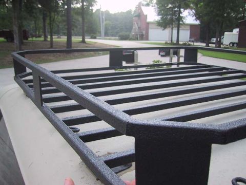 1995 Ford Bronco - A black aftermarket roof rack is installed on the roof of a vehicle, with a suburban landscape visible behind it.