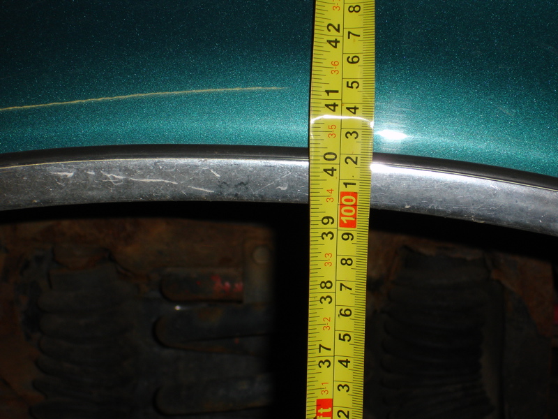 Measuring tape on a green vehicle fender above a tire