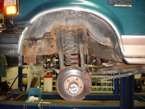 1996 Ford Bronco - Close-up of the rear suspension and wheel well of a 1996 Ford Bronco, showing signs of rust.