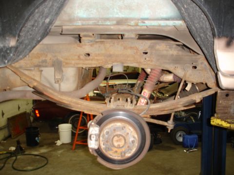 1996 Ford Bronco - The rear suspension and brake assembly of a vehicle is shown in detail, with other vehicles visible in the background.