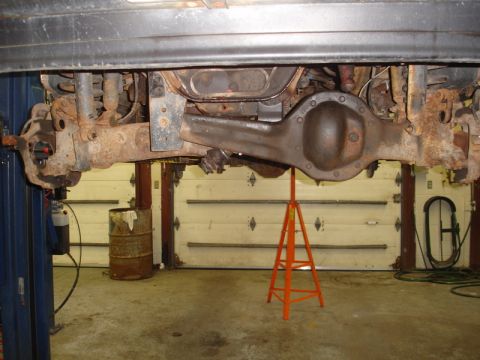 1996 Ford Bronco - The rear axle assembly of a vehicle is shown supported by jack stands in a garage setting.