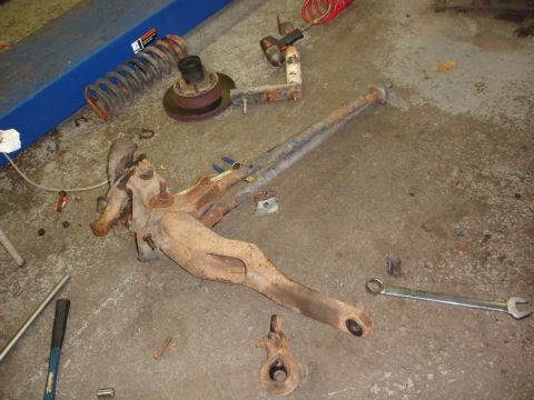 1996 Ford Bronco - Vehicle suspension components laid out on the floor, possibly for repair or replacement.