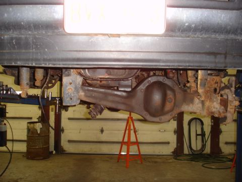 1996 Ford Bronco - The rear axle assembly of a vehicle is shown supported by jack stands in a garage setting.