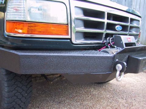 1995 Ford Bronco - Front view of a dark green Ford Bronco, showing its grille, headlights, and aftermarket winch bumper.