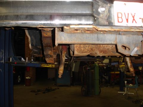 1996 Ford Bronco - The rear suspension and frame of a vehicle are visible while it is elevated on a lift, with significant rust present on the leaf springs an…