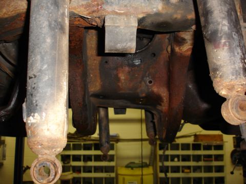 1996 Ford Bronco - Underside view of a heavily rusted vehicle's rear axle and suspension system.