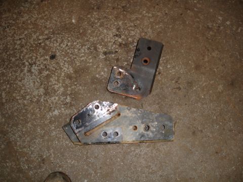 1996 Ford Bronco - Two metal brackets, likely for vehicle modification or repair, are shown on a concrete surface.