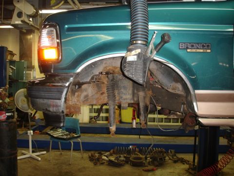 1996 Ford Bronco - Front suspension and fender of a 1996 Ford Bronco undergoing repairs in a workshop.