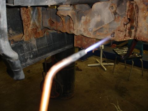 1996 Ford Bronco - A torch is used to heat a rusty section of a vehicle's frame during a repair.