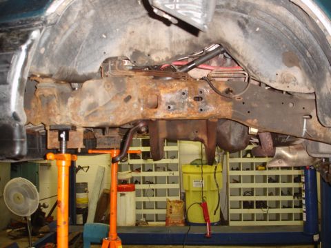 1996 Ford Bronco - Close-up view of heavily rusted frame and suspension parts of a vehicle undergoing repair.