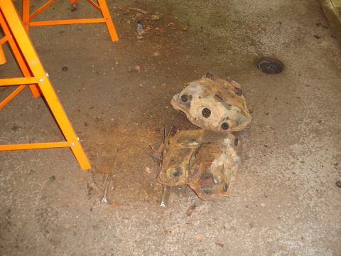 1996 Ford Bronco - Rusted automotive parts sit on a concrete floor, with an orange sawhorse visible to the left.