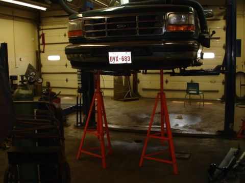 1996 Ford Bronco - Front view of a 1996 Ford Bronco being serviced in a garage, supported by jack stands.
