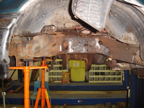 1996 Ford Bronco - The heavily rusted frame of a vehicle is visible, supported by jack stands during maintenance.