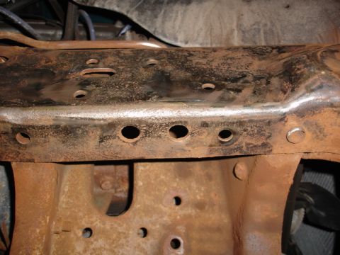 1996 Ford Bronco - A close-up view of a heavily rusted vehicle frame, showing numerous holes and signs of wear.