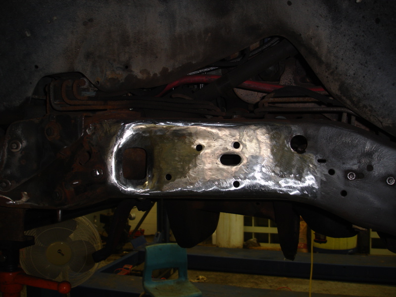 Vehicle frame section with shiny metal repair patch and visible holes