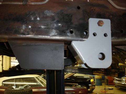 1996 Ford Bronco - A close-up view of a custom bracket installed on a vehicle's frame, with other vehicles visible in the background.