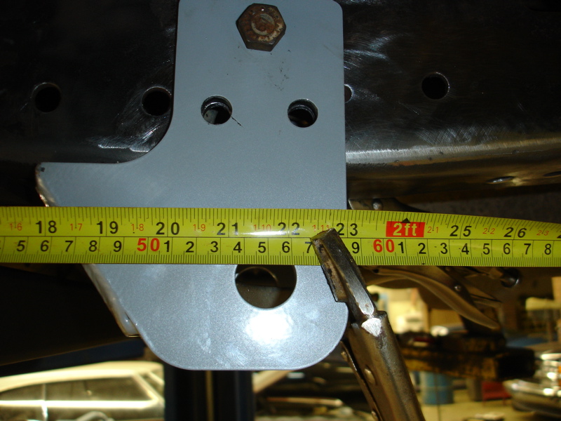 Close-up of a gray metal suspension bracket being measured with a yellow tape measure