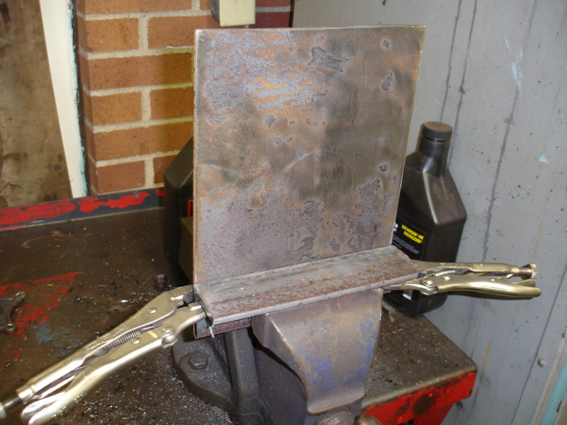 Metal plates held in a vise with locking pliers, ready for welding