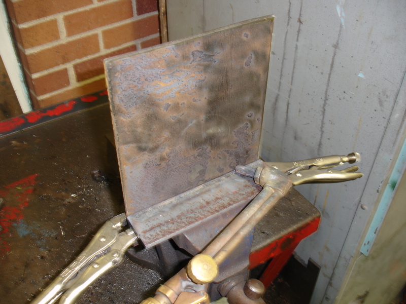 Metal plate held by vise grips and a welding torch