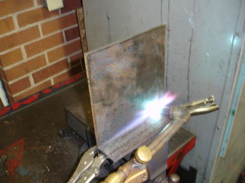 1996 Ford Bronco - A metal plate is being cut with a torch while secured in a vise.