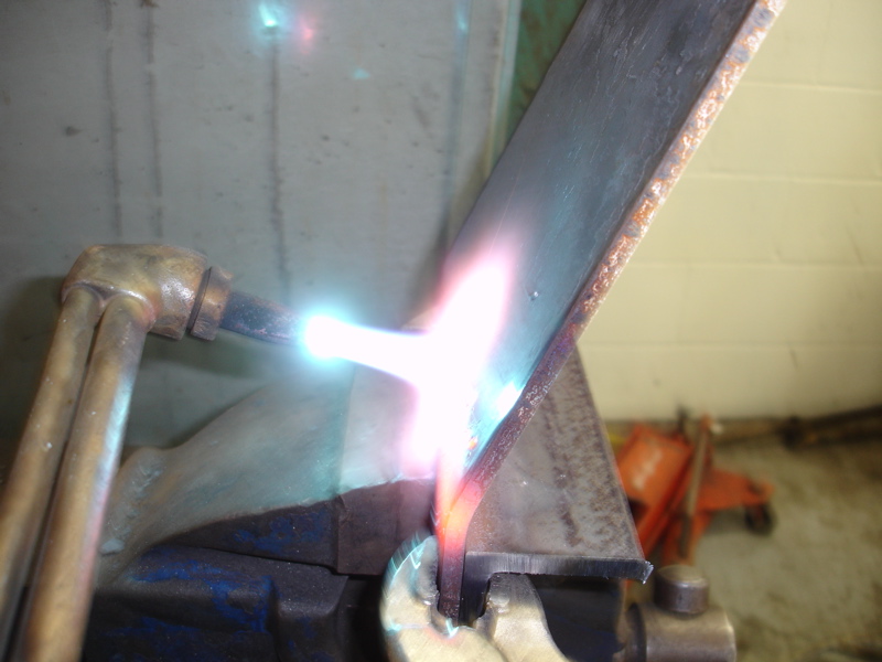 Oxy-acetylene torch flame cutting into a piece of metal held in a vise