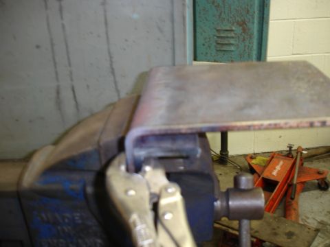 1996 Ford Bronco - A piece of metal is being bent in a vise with locking pliers in a workshop setting.