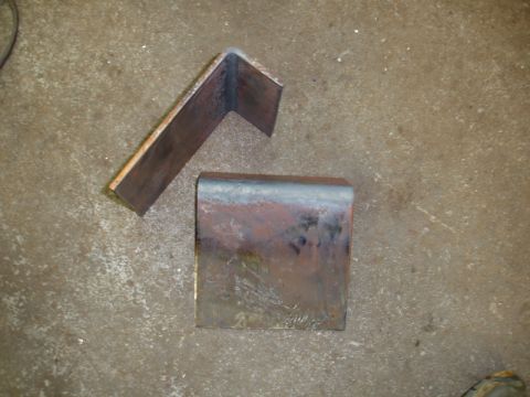1996 Ford Bronco - Two metal brackets, one L-shaped and one U-shaped, lie on a concrete surface.