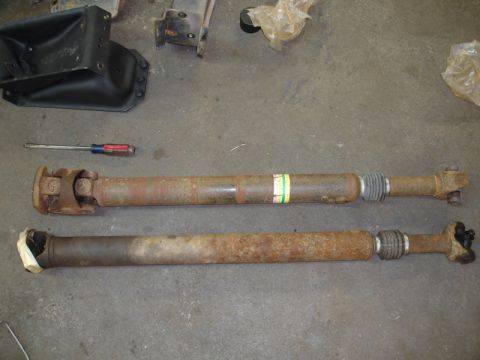 1996 Ford Bronco - Two driveshafts are laid out on a concrete surface, with a screwdriver nearby.