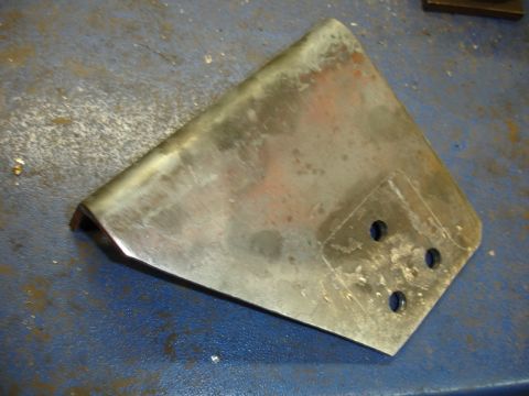 1996 Ford Bronco - A metal bracket with three drilled holes is shown on a blue workbench surface.