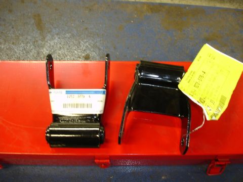 1996 Ford Bronco - Two black leaf spring shackle plates are shown on a red toolbox, one with a white label and the other with a yellow tag.