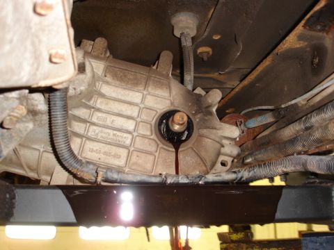 1996 Ford Bronco - Transmission fluid is seen leaking from a Borg Warner transfer case, indicating a potential issue with the vehicle's drivetrain.