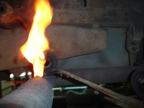 1996 Ford Bronco - A leaf spring is heated by a torch, likely for repair or modification.