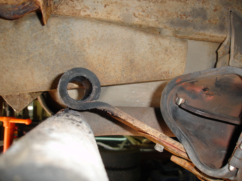 Close-up of a vehicle's leaf spring with a rubber bushing and part of the frame