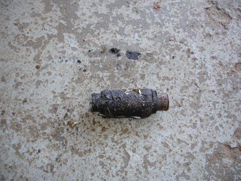 1996 Ford Bronco - A dirty exhaust pipe section lies on a cracked concrete surface.