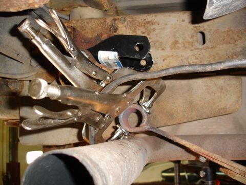 1996 Ford Bronco - Close-up of a vehicle's undercarriage, focusing on exhaust system work with vice grips.