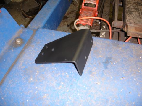 1996 Ford Bronco - A black metal bracket with multiple mounting holes sits on a blue surface, possibly in a workshop.