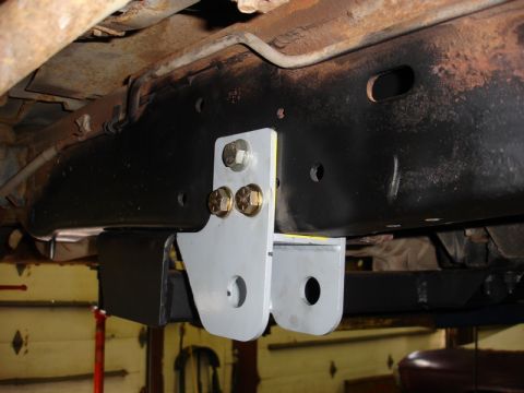 1996 Ford Bronco - An aftermarket bracket is attached to the underside of a vehicle's frame, showing a close-up of the mounting hardware.